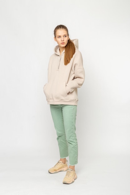 Chica en pantalones de carga verdes y sudadera con capucha beige aislada en blanco