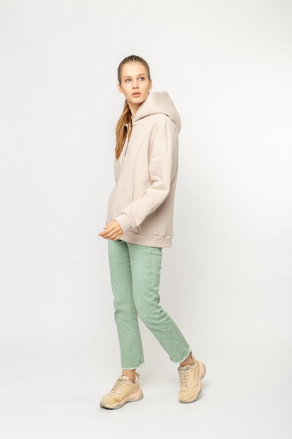 Chica en pantalones de carga verdes y sudadera con capucha beige aislada en blanco