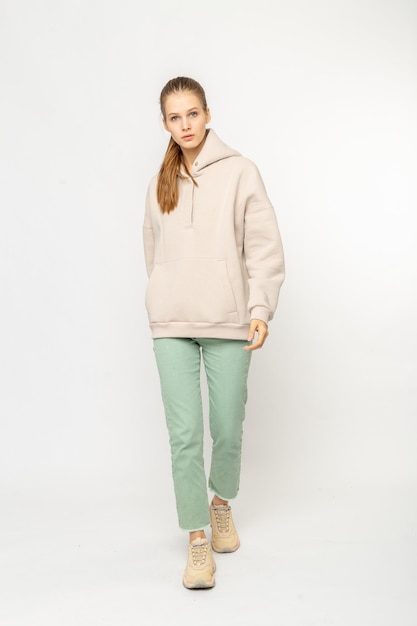 Chica en pantalones de carga verdes y sudadera con capucha beige aislada en blanco