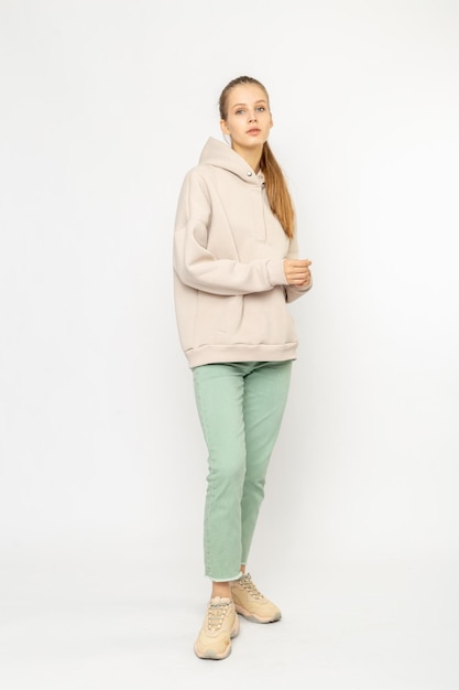 Chica en pantalones de carga verdes y sudadera con capucha beige aislada en blanco