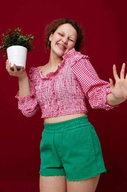 Chica en pantalones cortos verdes con un fondo rojo maceta inalterado