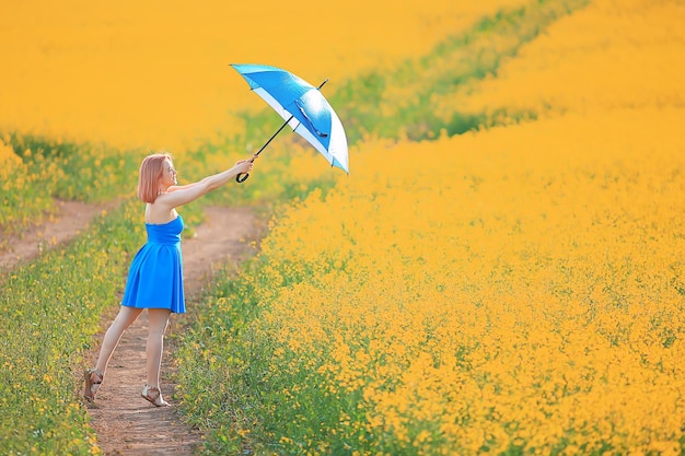 chica con un paraguas en un campo de flores de verano, campo amarillo de la naturaleza femenina del país