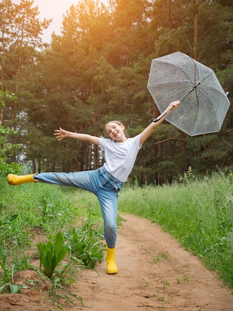 Chica con paraguas posa sonriendo contra el verde bosque lluvioso