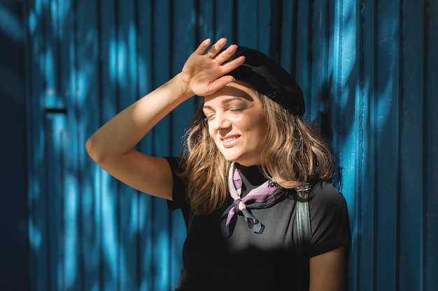 La chica de la pared azul en boina y falda, elegante francesa a la sombra de la ciudad