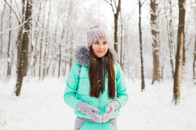 Chica en el parque de invierno cubierto de nieve. Concepto de nieve, frío y temporada.