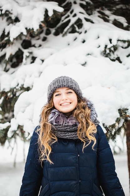 Chica en el parque de invierno cubierto de nieve