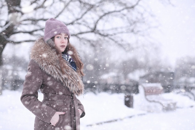 Chica en un parque de invierno por la tarde en nevadas