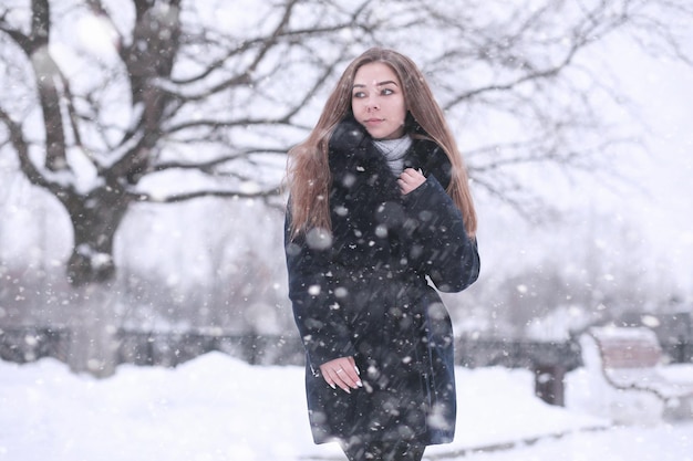 Chica en un parque de invierno por la tarde en nevadas