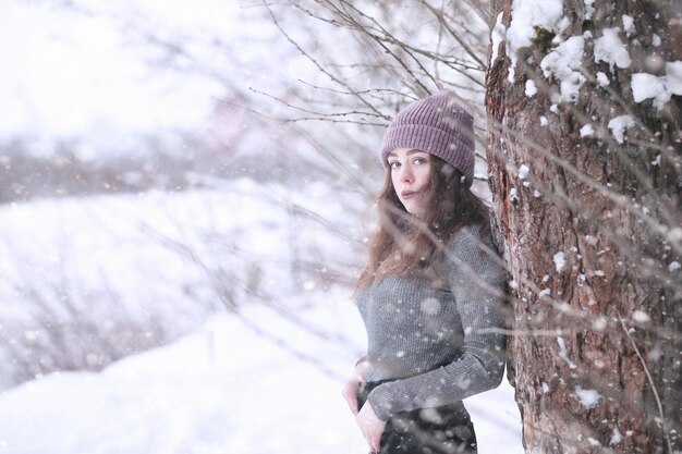 Chica en un parque de invierno por la tarde en nevadas