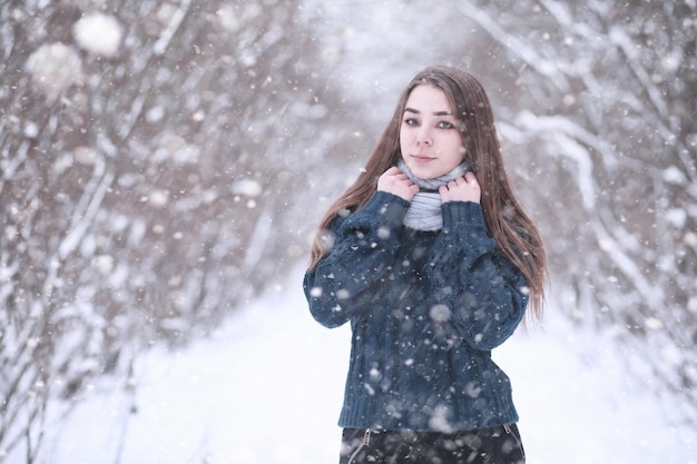 Chica en un parque de invierno por la tarde en nevadas