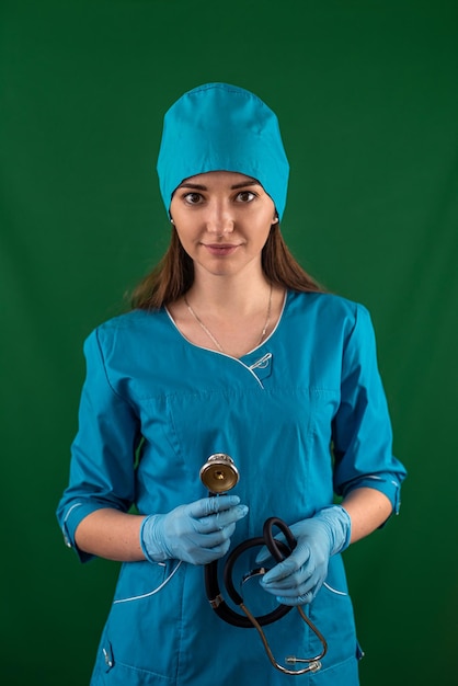 Foto chica pasante se encuentra en el fondo en una bata blanca con un estetoscopio