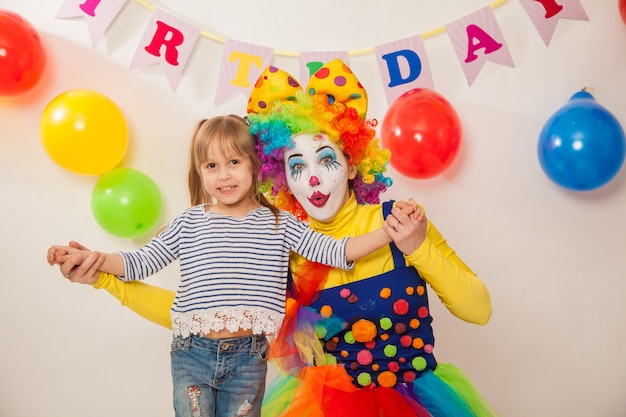 Chica payaso alegre en la fiesta juega con la cumpleañera