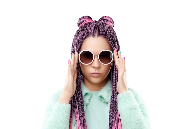 Chica con peinado de trenzas rosa en ropa turquesa y gafas de sol aislar sobre un fondo blanco. Concepto de estilo moderno, inclusión, espacio de copia.