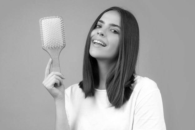 Chica peinando el cabello hermosa joven sosteniendo el peine alisado el cabello