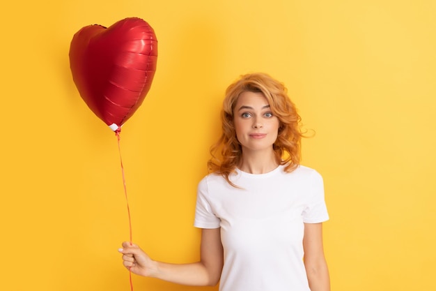 Chica pelirroja asombrada con globo de corazón de amor. caridad y donacion