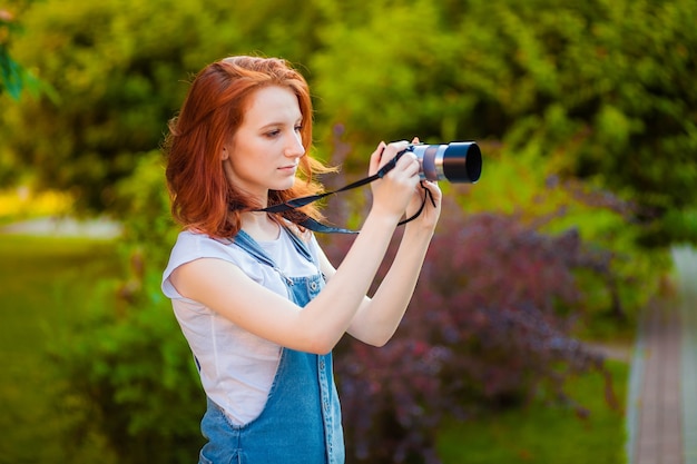 Chica pelirroja con una cámara tomando fotografías en el parque