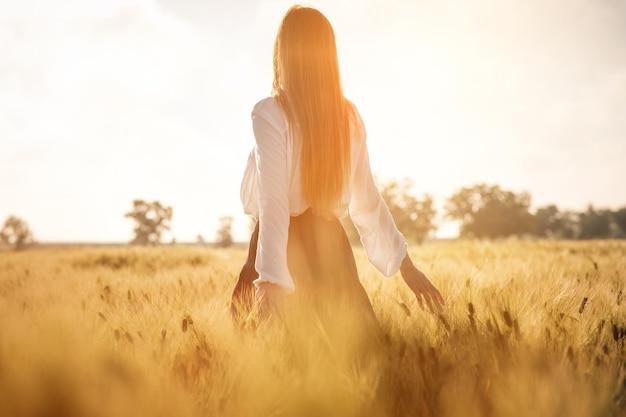 Chica pelirroja en un campo de trigo al atardecer Hermosa mujer en campo dorado al atardecer Tonos cálidos retroiluminados