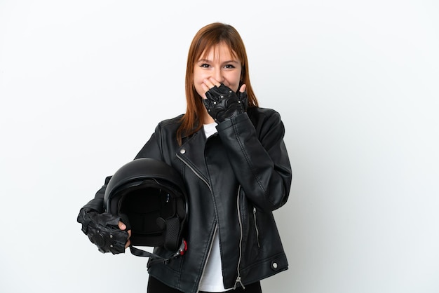 Chica pelirroja con un casco de motocicleta aislado sobre fondo blanco feliz y sonriente cubriendo la boca con la mano