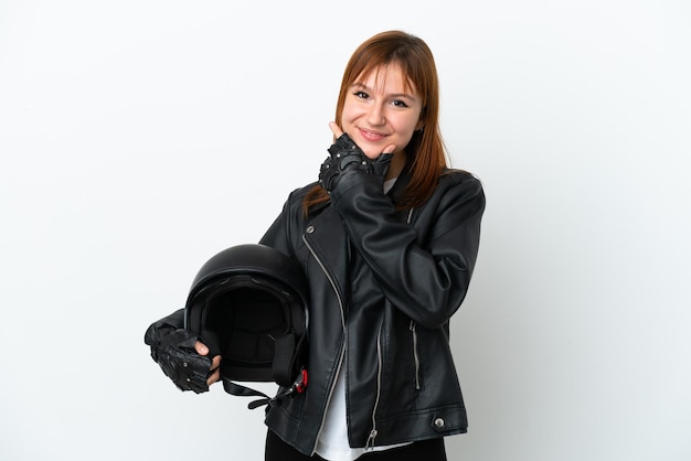 Chica pelirroja con un casco de motocicleta aislado sobre fondo blanco feliz y sonriente