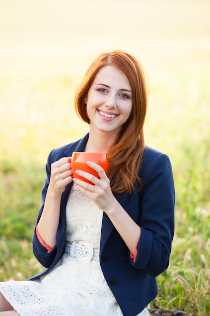 Chica pelirroja con copa naranja al aire libre