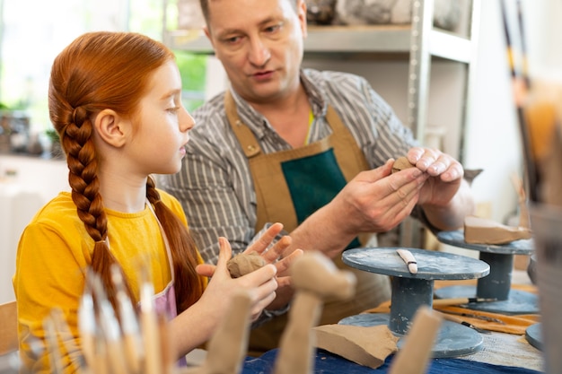 Chica pelirroja creativa inteligente escuchando al profesor de arte