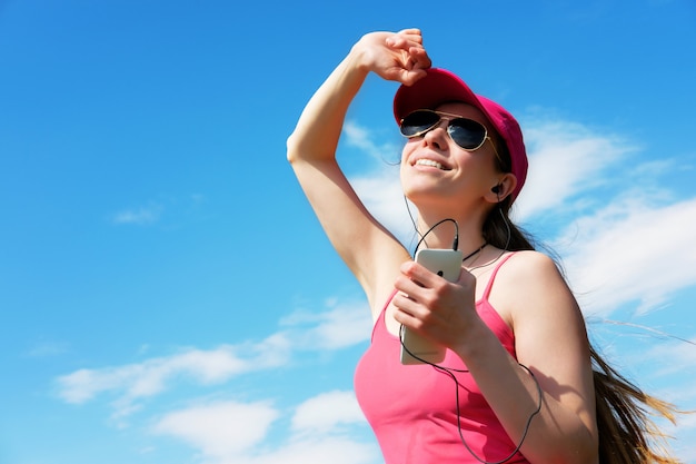 Foto chica pelirroja está escuchando música durante trotar en verano, copia espacio