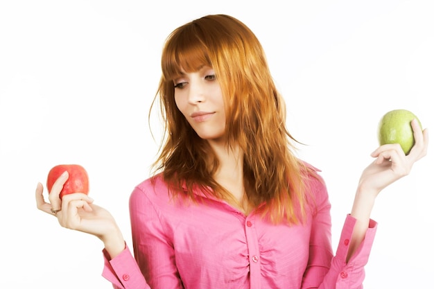 Chica pelirroja con manzana sobre fondo blanco.