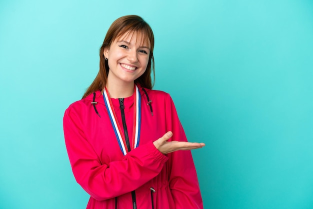 Chica pelirroja con medallas aisladas o fondo azul presentando una idea mientras mira sonriendo hacia