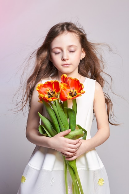 Chica pelirroja de moda con tulipanes en las manos. Foto del estudio