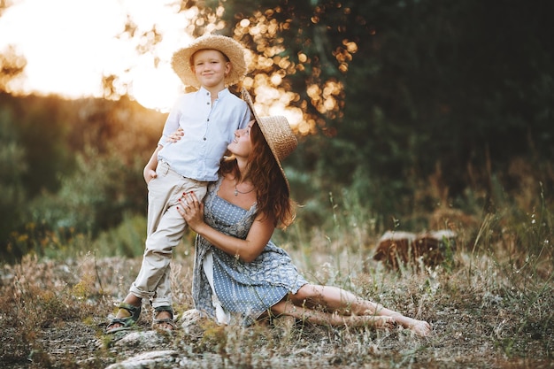 Chica pelirroja con un niño en el contexto de una puesta de sol. Linda madre con un bebé rubio