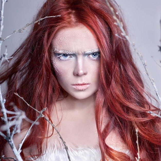 Chica pelirroja con el pelo largo, una cara cubierta de nieve con escarcha.