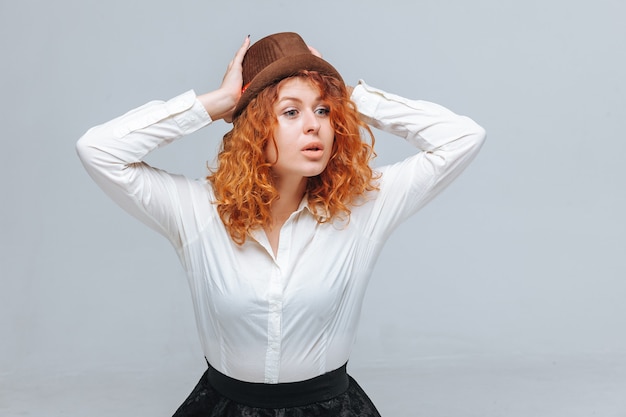 Chica pelirroja con sombrero marrón y camisa blanca