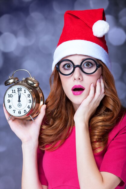 Chica pelirroja en sombrero de navidad con reloj