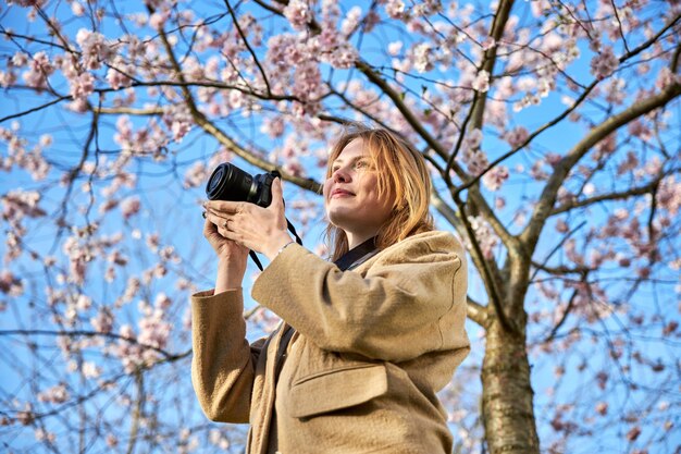 Chica pelirroja tomando fotos frente a los cerezos en flor