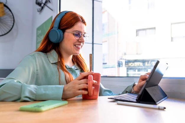 Foto chica pelirroja vibra en el trabajo impresionante pelirroja disfrutando del café y el trabajo remoto