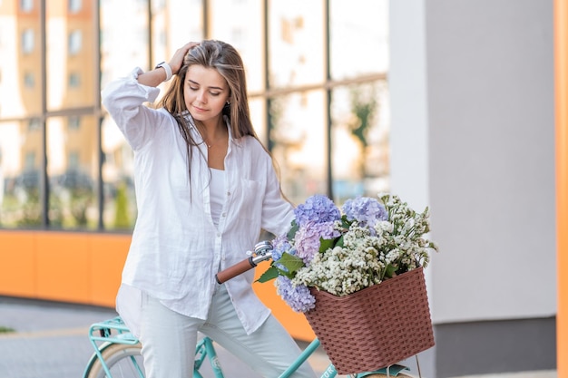 Chica de pelo largo con bicicleta y flores.