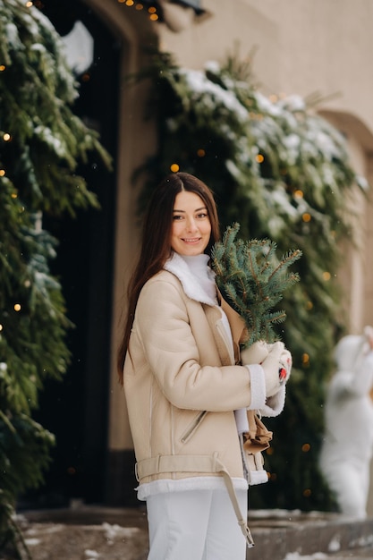 Una chica con el pelo largo en invierno en la calle con un ramo de ramas de abeto frescas