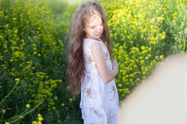 Una chica con el pelo largo y oscuro sobre un fondo de hierba amarilla.