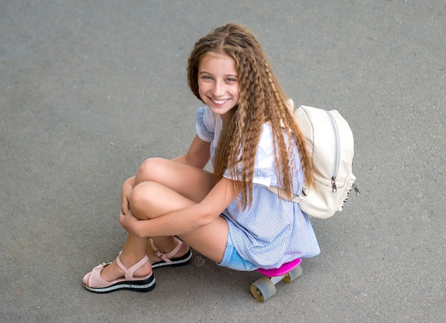 Chica con el pelo largo sentado en patinaje