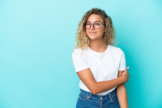 Foto chica con pelo rizado aislado sobre fondo azul riendo