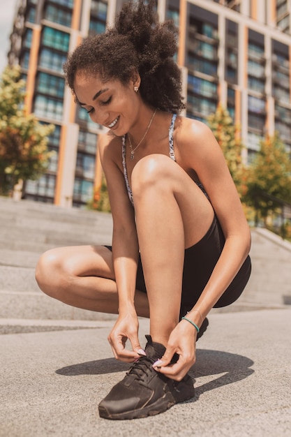 Chica de pelo rizado atando sus zapatillas durante el ejercicio