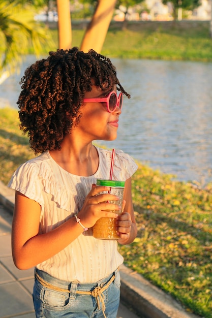 Chica con el pelo rizado caminando en un parque durante las vacaciones Concepto de verano