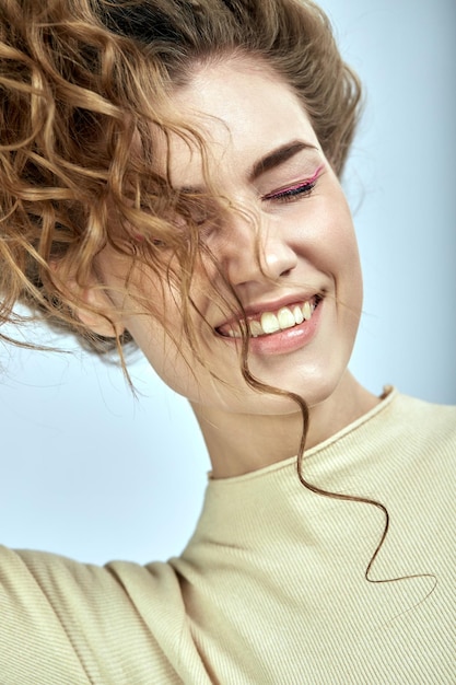 Foto la chica de pelo rizado está jugando con su cabello