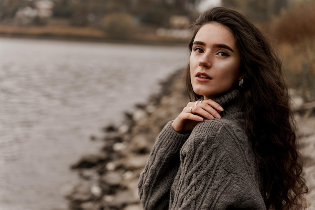 Chica con el pelo rizado junto al lago en otoño