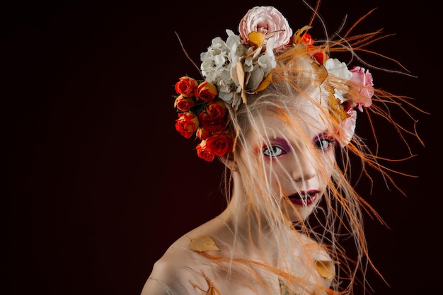 Una chica con el pelo rizado y vivo y flores en la cabeza. Objeto de arte. Hada de las flores