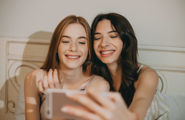 chica con pelo rojo y pecas está sonriendo cerca de su amiga morena