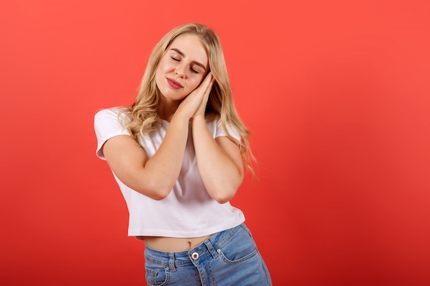 Chica de pelo rubio hermosa cansada con los ojos cerrados que se inclina