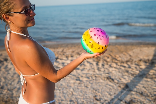 Chica con una pelota cerca del mar.