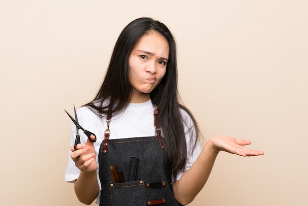 Chica de peluquería adolescente haciendo gesto de dudas mientras levanta los hombros