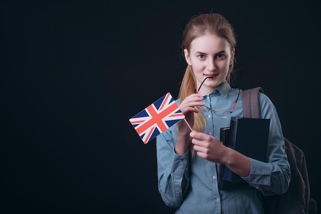 Chica pensativa con bandera británica tocándose el labio con gafas auricular